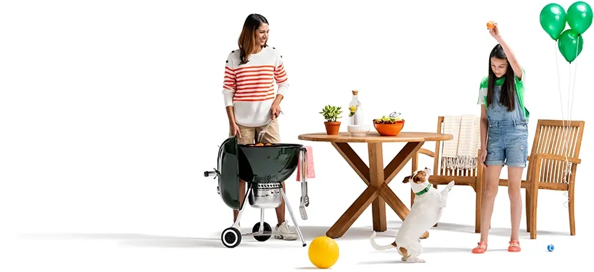 A woman grills as her daughter plays with their dog. Green balloons are tied to the patio chair.